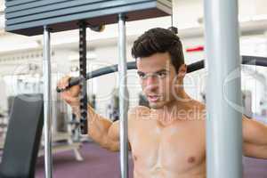 Muscular man exercising on a lat machine in gym