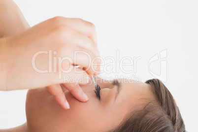Close-up side view of hand plucking eyelashes