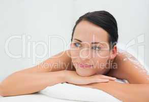 Peaceful brunette lying with salt scrub on back