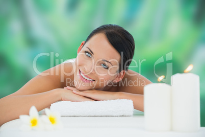 Beautiful brunette relaxing on massage table smiling at camera