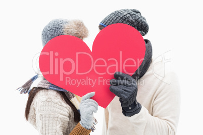 Attractive young couple in warm clothes holding red heart