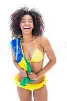 Fit girl in yellow bikini holding brazil flag smiling at camera