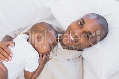 Happy young father napping with baby son on couch