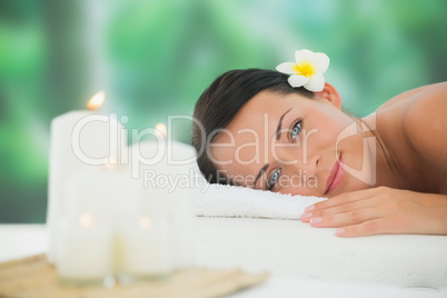 Beautiful brunette relaxing on massage table smiling at camera