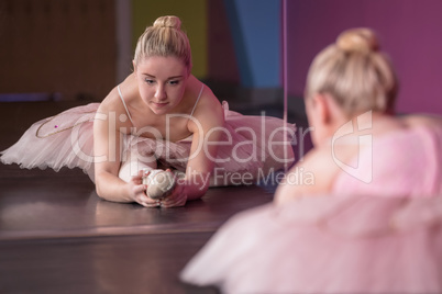 Graceful ballerina warming up in front of mirror