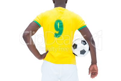 Football player in yellow standing with the ball