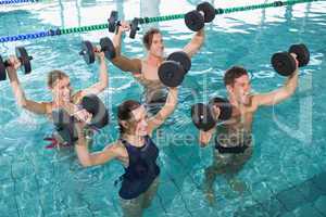 Happy fitness class doing aqua aerobics with foam dumbbells