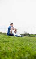 Football player in blue taking a break on the pitch