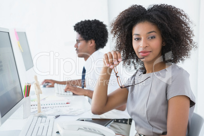 Young editor smiling at camera at her desk