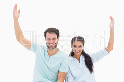 Cute couple sitting with arms raised