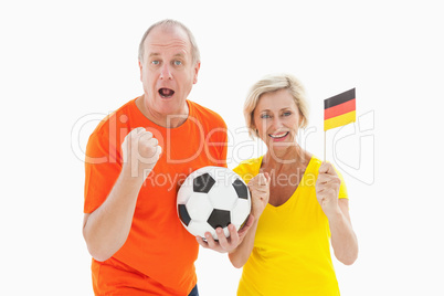 Happy german couple cheering at camera holding ball