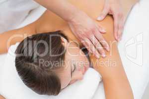 Attractive young woman receiving shoulder massage at spa center