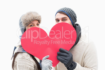 Attractive young couple in warm clothes holding red heart