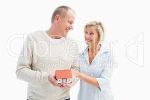 Happy mature couple with model house