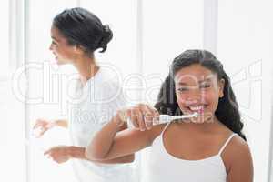 Pretty mother brushing her teeth with her daughter