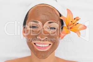 Smiling brunette getting a mud treatment facial