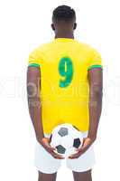 Football player in yellow standing with the ball