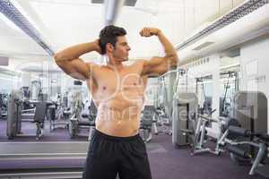 Shirtless muscular man flexing muscles in gym