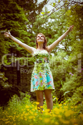 Woman with arms outstretched in field against trees