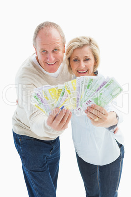 Happy mature couple smiling at camera showing money