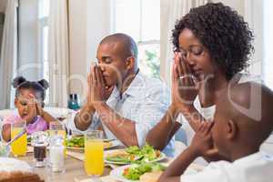 Happy family saying grace before meal