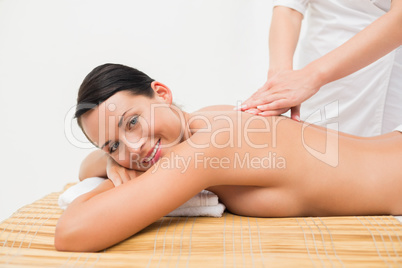 Beautiful brunette enjoying a back massage smiling at camera