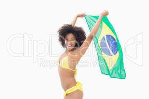 Athletic girl in yellow bikini holding brazil flag