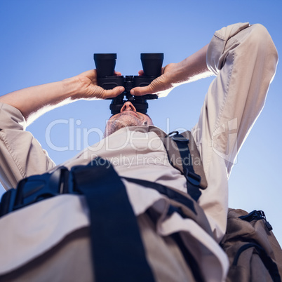 Hiker looking through binoculars on country trail