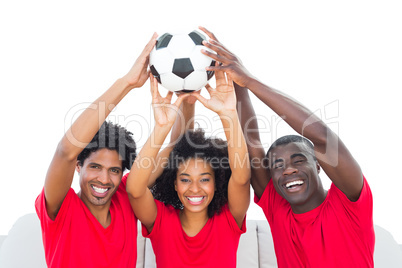 Happy football fans in red holding up ball