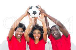 Happy football fans in red holding up ball