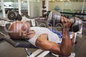 Muscular man exercising with dumbbells