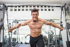 Shirtless muscular man using resistance band in gym