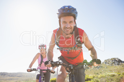 Fit cyclist couple riding together on mountain trail