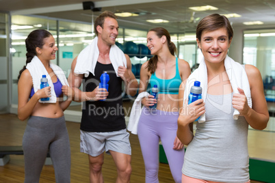 Fit woman smiling at camera in busy fitness studio