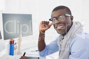 Hipster businessman smiling at camera at his desk