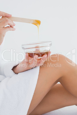 Woman holding hot wax in bowl at spa center