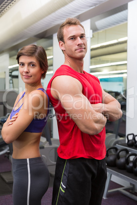 Fit attractive couple smiling at camera with arms crossed