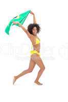 Fit girl in yellow bikini holding brazil flag smiling at camera