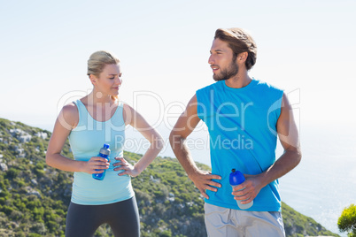 Fit couple standing holding water bottles