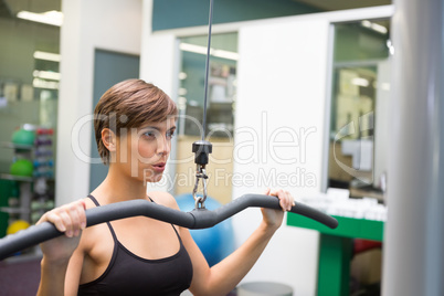 Fit brunette using weights machine for arms