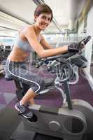 Fit smiling woman working out on the exercise bike