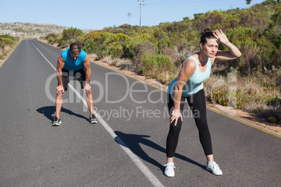 Athletic couple taking a break from jogging on the open road