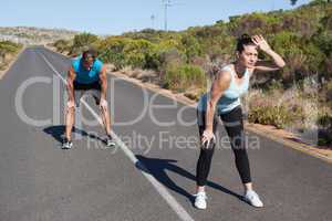 Athletic couple taking a break from jogging on the open road