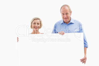 Mature couple smiling at camera holding card