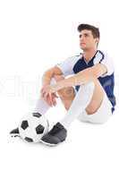 Football player sitting on the ground with ball