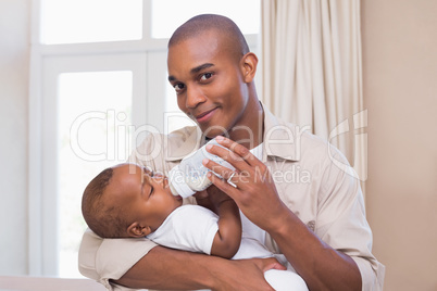 Happy father feeding his baby boy a bottle