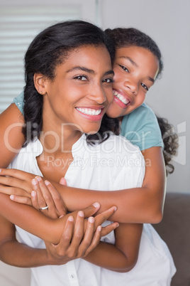 Happy mother and daughter hugging on the couch