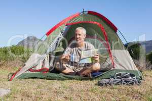 Happy camper looking at map sitting in his tent