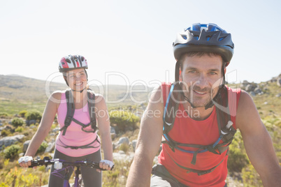 Fit cyclist couple riding together on mountain trail