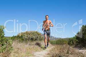 Shirtless man jogging with heart rate monitor around chest